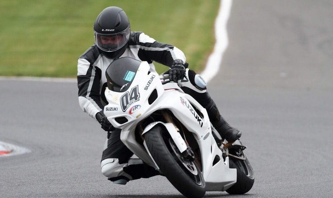 A motorcyclist leaning into a sharp turn on a paved racetrack.