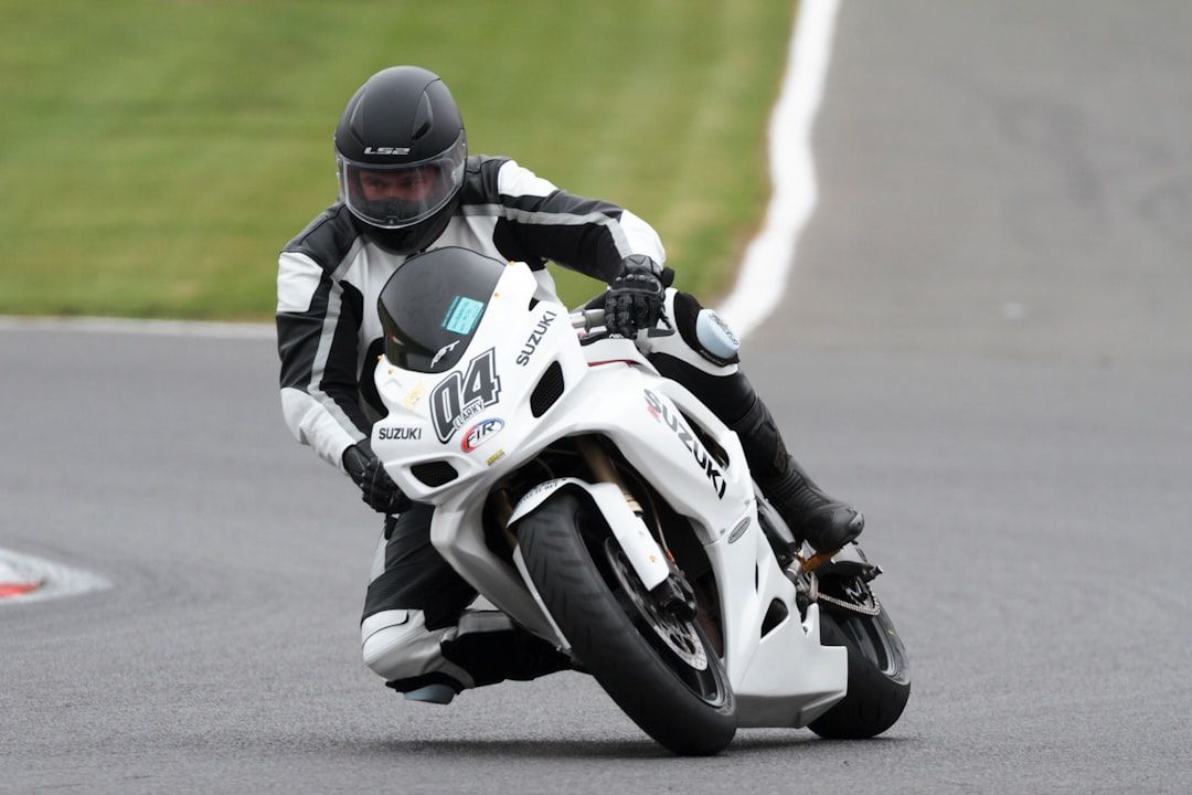 A motorcyclist leaning into a sharp turn on a paved racetrack.